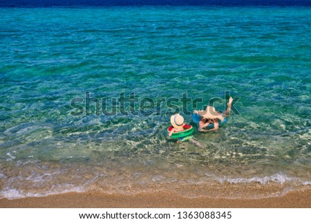 Two year old toddler boy on beach with mother swimming with inflatable ring. Summer family vacation. Sithonia, Greece. 