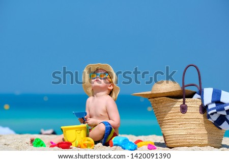 Two year old toddler boy playing with beach toys on beach 