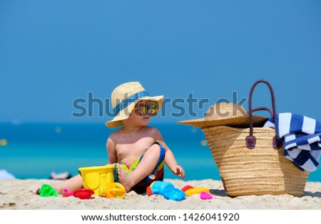 Two year old toddler boy playing with beach toys on beach 