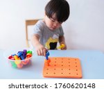 Two years old asian child boy playing with Stackers Peg Board at home. educational toys concept. Development of kids fine motor skills, imagination and logical thinking.  Selective focus