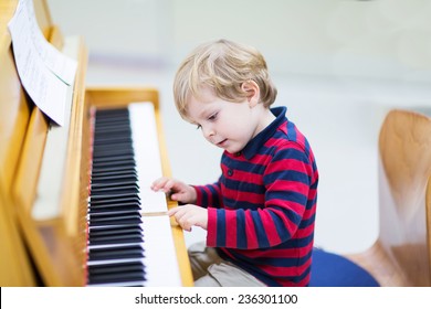 Two Years Old Funny Positive Toddler Child Playing Piano. Early Music Education For Little Kids. Child At School, Learning Music Instrument.