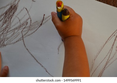 Two years old toddler - boy and one of his first trying how to draw. Little baby is playing and drawing on a white paper. Brown crayon in toddler's hand.  - Shutterstock ID 1499569991
