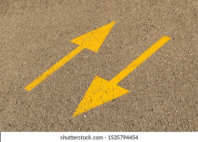 Two yellow arrows on the pavement indicate the opposite direction, as a symbol of contradiction