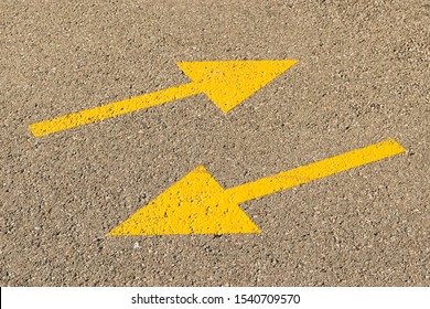 Two yellow arrows on the pavement indicate the opposite direction, as a symbol of contradiction