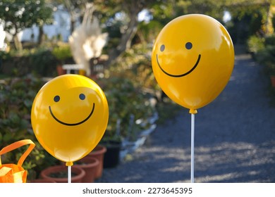 Two yellow balloons decorated with smileys
