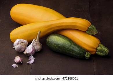 Two yellow big and medium and small green zucchini on wooden table.And garlic,chiveFamily of zuccini.