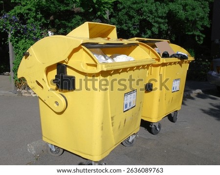 Two yellow plastic selective waste collection containers in a residential area.