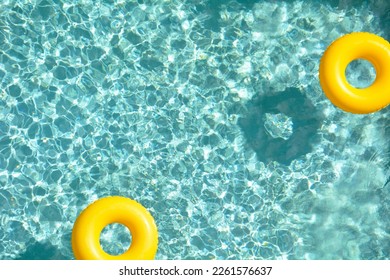 Two yellow pool rings floating in a cool blue swimming pool. Room for your copy. - Powered by Shutterstock