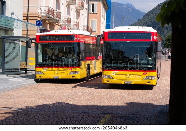 Two yellow post buses at bus station at City\
of Bellinzona on a sunny late summer noon. Photo taken September\
11th, 2021, Bellinzona,\
Switzerland.