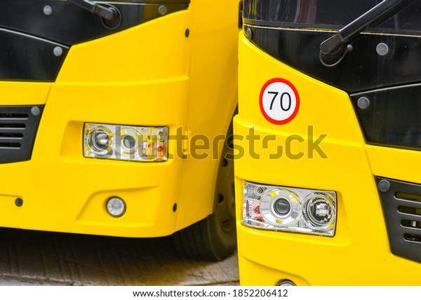 Two yellow school buses and a speed limit\
sign (70 kilometers)