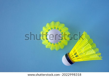 Two yellow shuttlecocks on a blue background with copy space