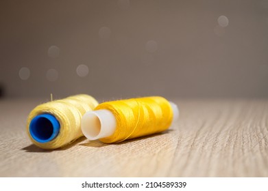 Two yellow spools of thread on the table on a blurry background