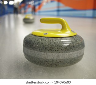 Two yellow stones for game in curling on ice.
