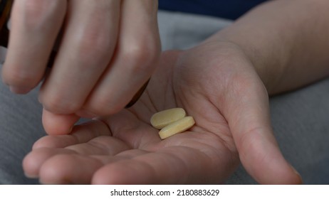 Two yellow tablets are poured on the palm of the hand to treat serious diseases. The patient takes pills that the doctor prescribed to him for the treatment of an infectious disease. - Powered by Shutterstock