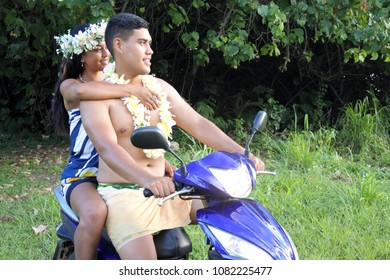 Two Young Adult Happy Pacific Islanders Couple Riding On A Motor Scooter In Rarotonga, Cook Islands. Real People Copy Space