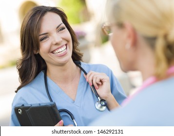 Two Young Adult Professional Female Doctors Or Nurses Talking Outside.