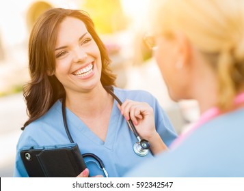 Two Young Adult Professional Female Doctors Or Nurses Talking Outside.