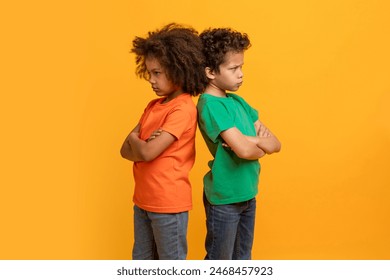 Two young African American boys appear to be in a moment of conflict or disagreement, standing back to back with their arms crossed and stubborn expressions - Powered by Shutterstock