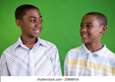 Two young African American males smiling at each other as friends or brothers do.