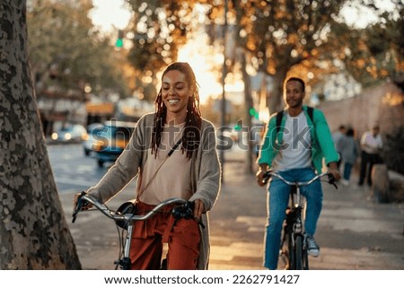 Two young African American people are outside in the city riding their bicycles on a beautiful sunny day.
