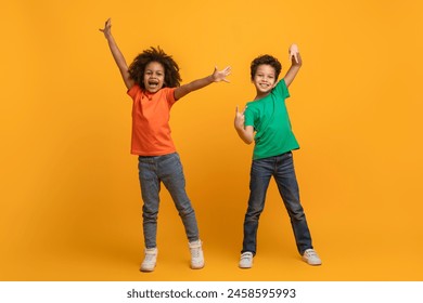 Two young African American siblings are standing with their arms raised in excitement and big smiles on their faces, expressing joy and celebration against a vibrant yellow backdrop. - Powered by Shutterstock