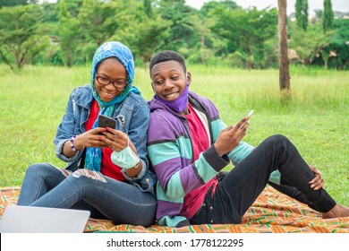 two young africans using their mobile phones together, sitting in a park - Shutterstock ID 1778122295