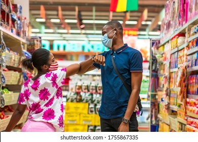 Two young Africans wearing face mask for protection,shopping in a supermarket, greeting each other with elbow, practicing social distancing - Black millennial healthy lifestyle in covid-19 pandemic