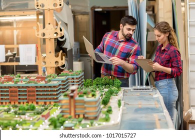 Two young architects reading working notes in notepad and searching in the net while preparing new project