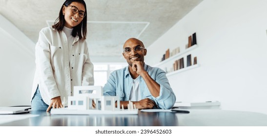 Two young architects working on a 3D house model in an office. Creative young business people planning a new design project. - Powered by Shutterstock