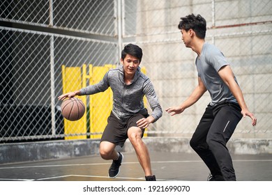 Two Young Asian Adult Men Playing One-on-one Basketball On Outdoor Court