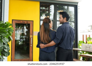 Two young Asian baristas Stand and admire your own shop. The successful birthday shop is a coffee shop, a small family business, a woman holding a bouquet of flowers. and turned and smiled happily. - Powered by Shutterstock