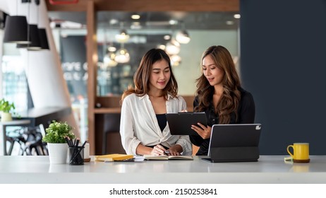 Two young Asian business woman talk, consult, discuss working with new startup project idea presentation analyze plan marketing and investment in the office. - Powered by Shutterstock