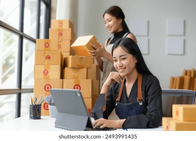 Two young asian businesswomen working together in their warehouse, checking stock and using digital tablet for online sales - Powered by Shutterstock