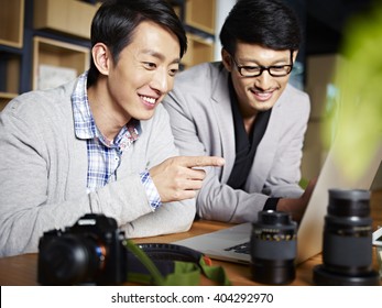 two young asian photographers designers selecting pictures using laptop computer in studio. - Powered by Shutterstock