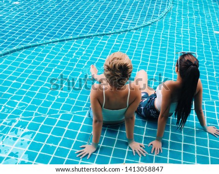Two young Asian woman relaxing by the pool.