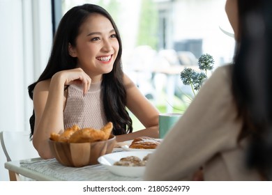 Two young Asian women friends talking at a coffee shop - Powered by Shutterstock