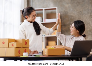 Two Young Asian women are happy and excited after a new order from SME customer, commercial checking, online marketing, Entrepreneur packing boxes, SME sellers, and freelance online sales concept, 