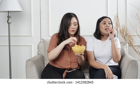 Two Young Asian Women Sharing Tortilla Chips