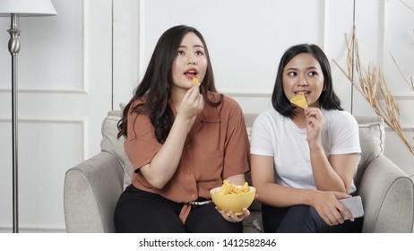 Two Young Asian Women Sharing Tortilla Chips