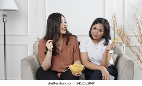 Two Young Asian Women Sharing Tortilla Chips