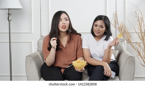 Two Young Asian Women Sharing Tortilla Chips