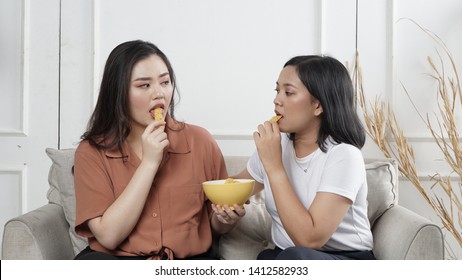 Two Young Asian Women Sharing Tortilla Chips