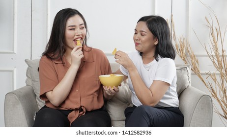 Two Young Asian Women Sharing Tortilla Chips