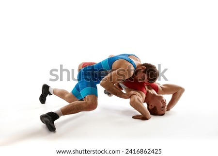 Two young athlete man, skilled wrestlers in red and blue uniform wrestling in motion against white studio background. Concept of sport, mixed martial arts, active lifestyle, movement.