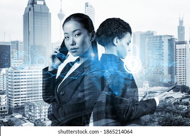 Two young attractive businesswoman in suits working on project to protect clients confidential information at cybersecurity compliance division. IT lock icons over Kuala Lumpur background. - Powered by Shutterstock