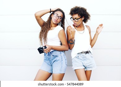 Two young beautiful afro girls are walking through the city and listen to music. Outdoors, lifestyle - Powered by Shutterstock