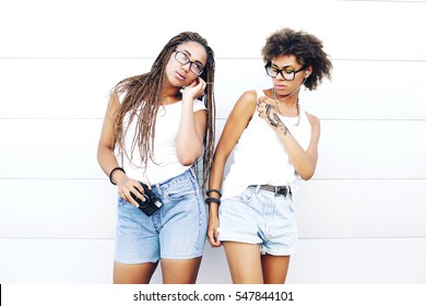 Two young beautiful afro girls are walking through the city and listen to music. Outdoors, lifestyle
