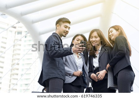 Two young beautiful businesswoman in black suit looking at file with big modern city building background, planning big new business project.