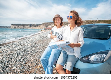 Two young beautiful female friends travel together by car, look at the road map against the sea, vacation, happiness, navigation, map - Powered by Shutterstock