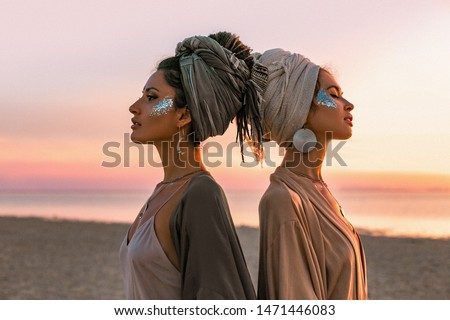 two young beautiful girls in turban on the beach at sunset 